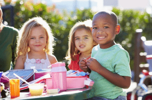 Outdoor photo of three children eating lunch