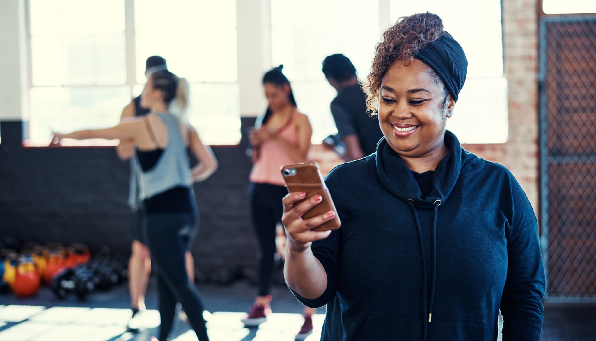 A woman looking at her phone and smiling before an exercise class