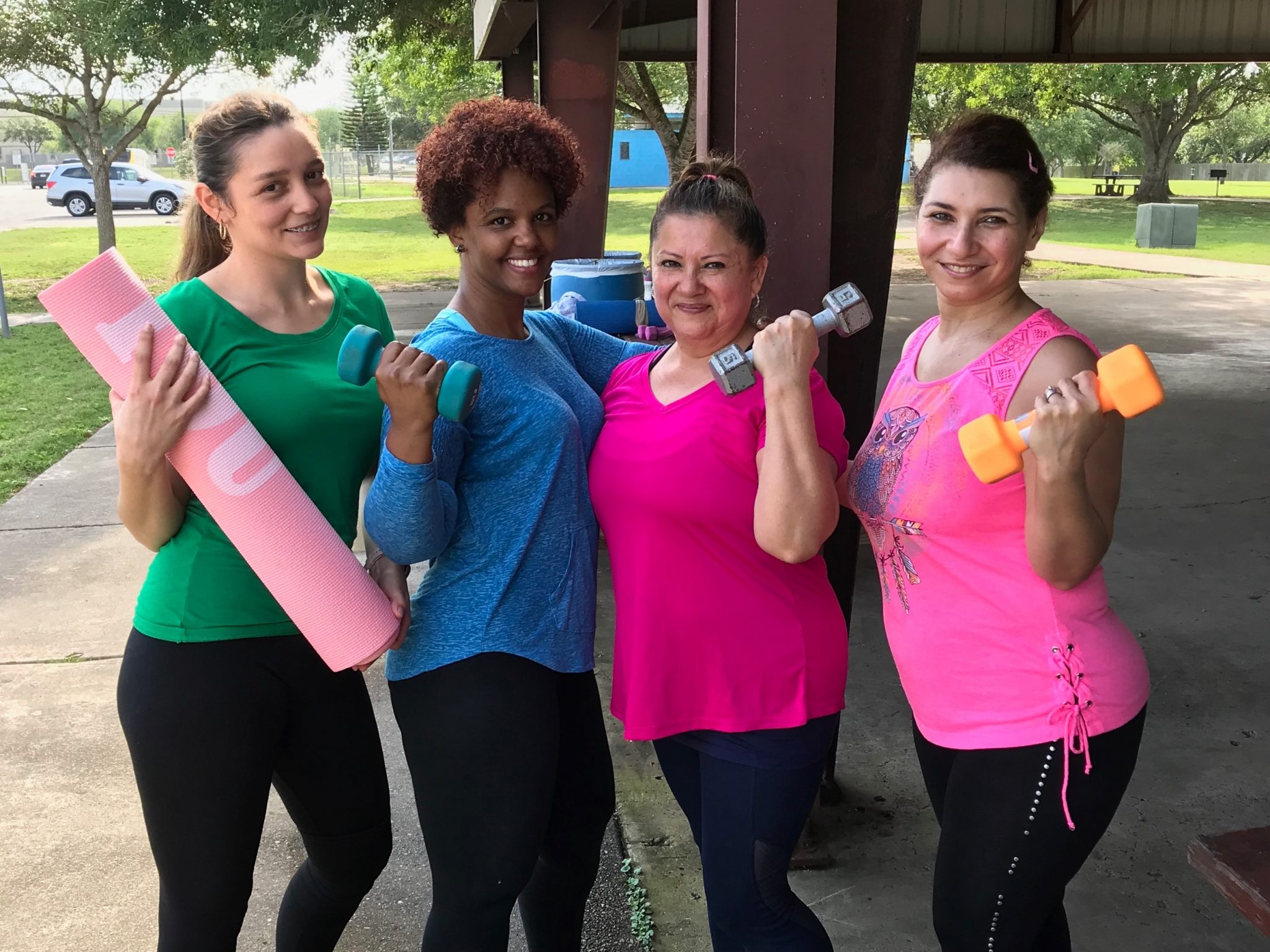 Cuatro mujeres posando para una foto antes de hacer ejercicio al aire libre