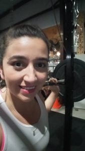 Cassandra at the gym, performing squats on the squat rack.