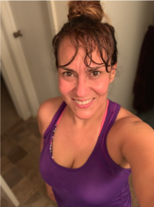 A selfie of a woman in a purple tank top after working out.