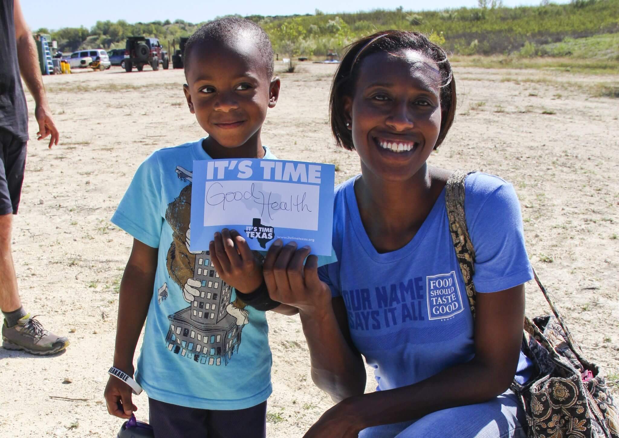 A woman and her child holding a sign that says It's Time for Good Health